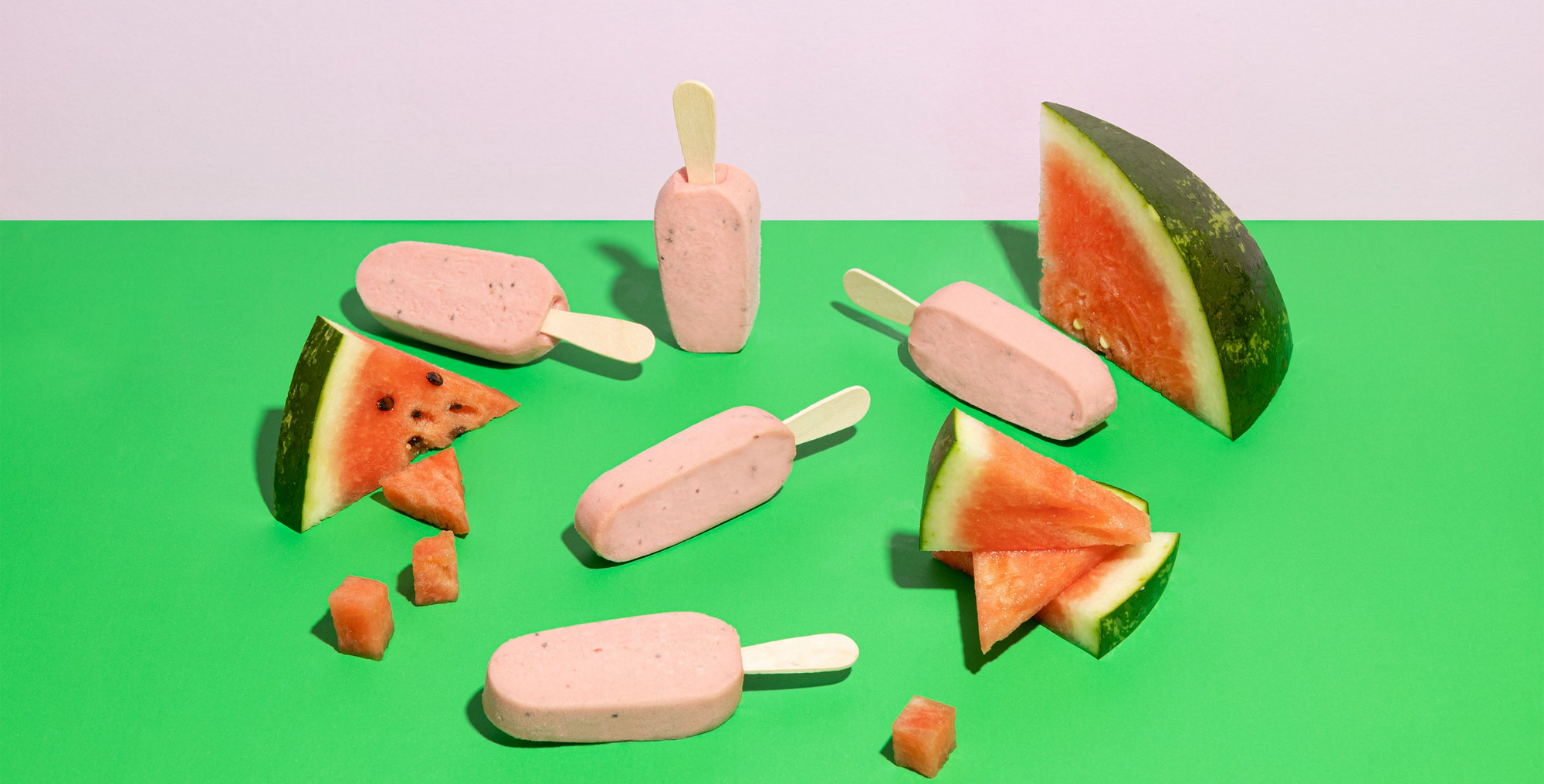 Pink popsicles with watermelon slices on a green and pink background