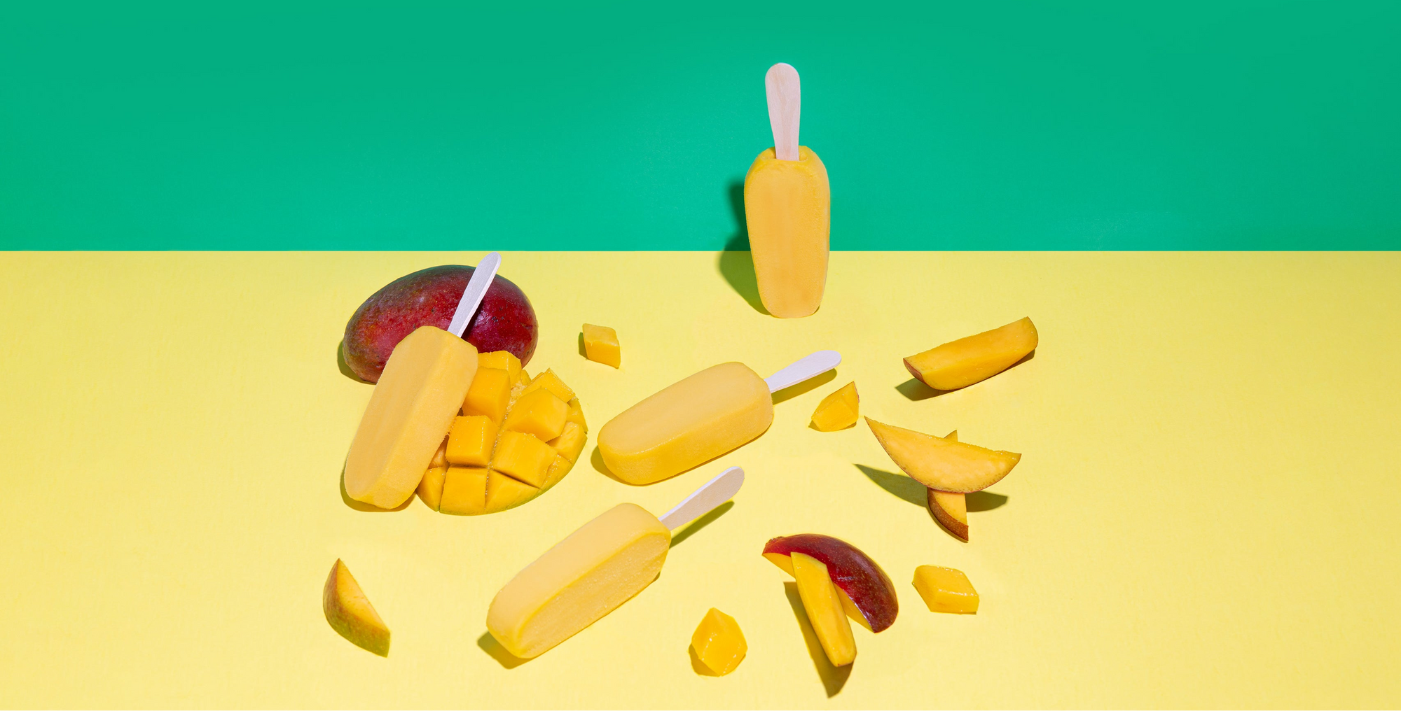 Mango-themed popsicles and slices on a yellow and green background